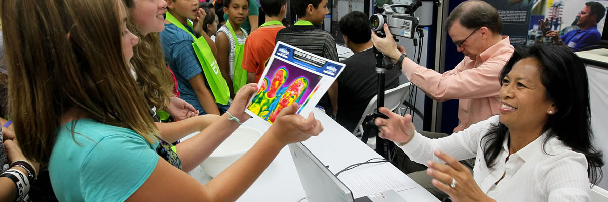 Presenter handing excited student a infrared image of her.